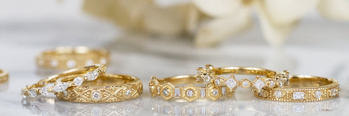 Assorted gold diamond bridal rings on marble surface with soft neutral background