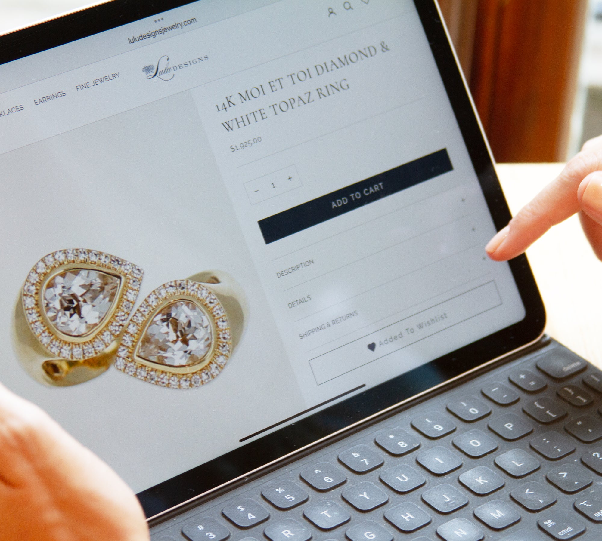 Hand adding diamond and white topaz ring to wishlist on jewelry product page tablet screen