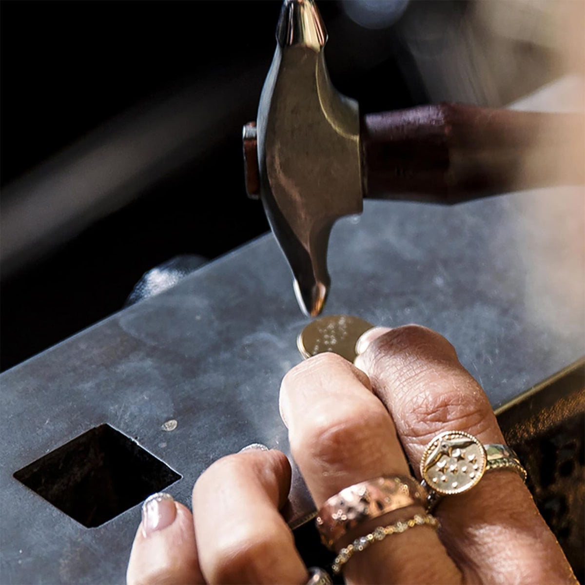 Hands working on a ring with a jewelry tool.